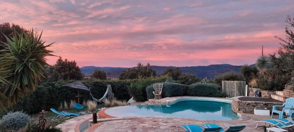 A swimming pool with a stone deck, surrounded by greenery and a view of distant mountains.