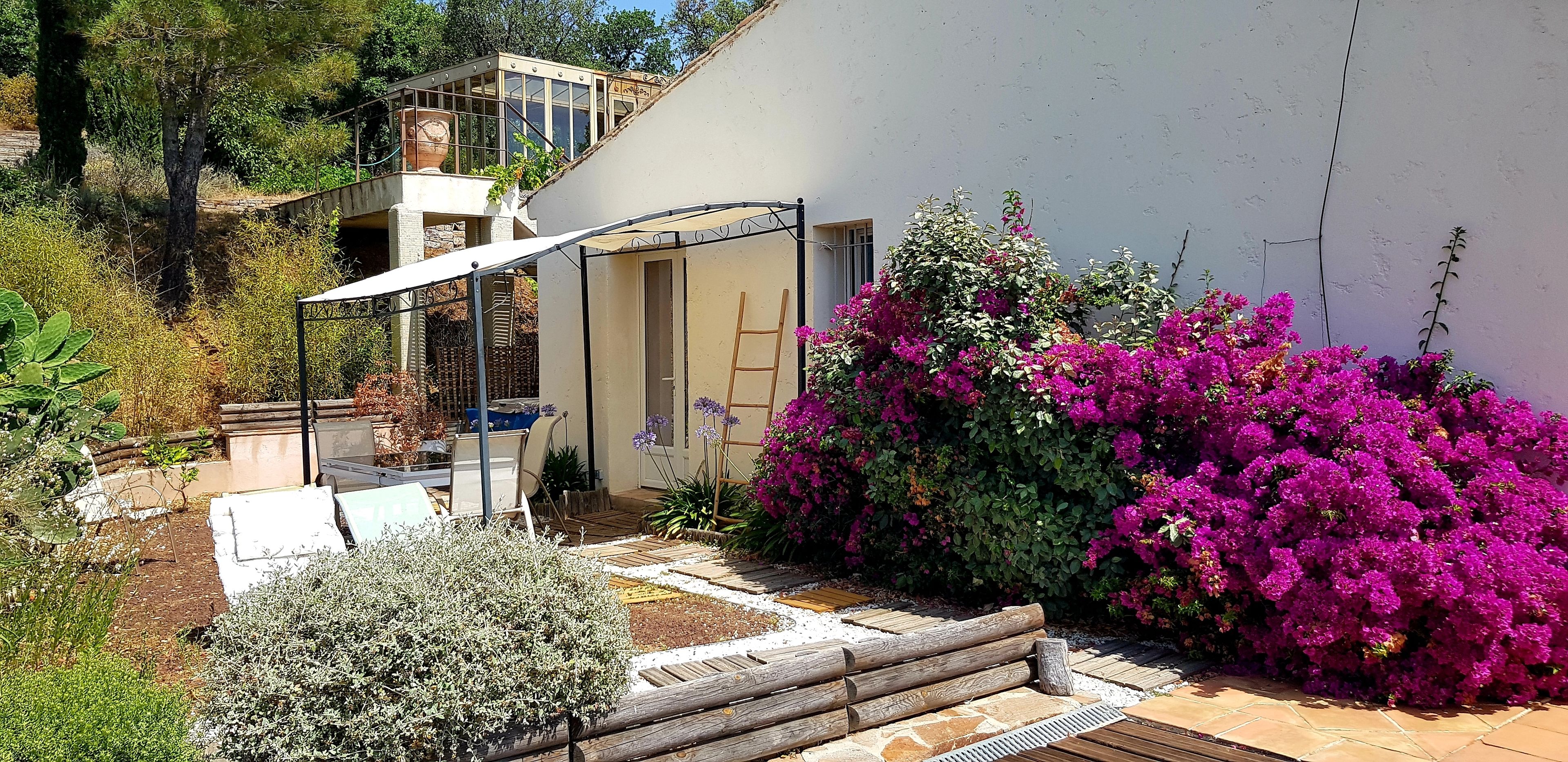 Une maison moderne dotée d’un patio, d’une véranda et de magnifiques arbustes de bougainvilliers aux couleurs vives.