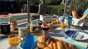 A breakfast table with croissants, fruit, and a Buddha statue in the background.