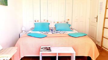 A bedroom with a bed, a bedside table, a wall-mounted lamp, and a door with a ladder.