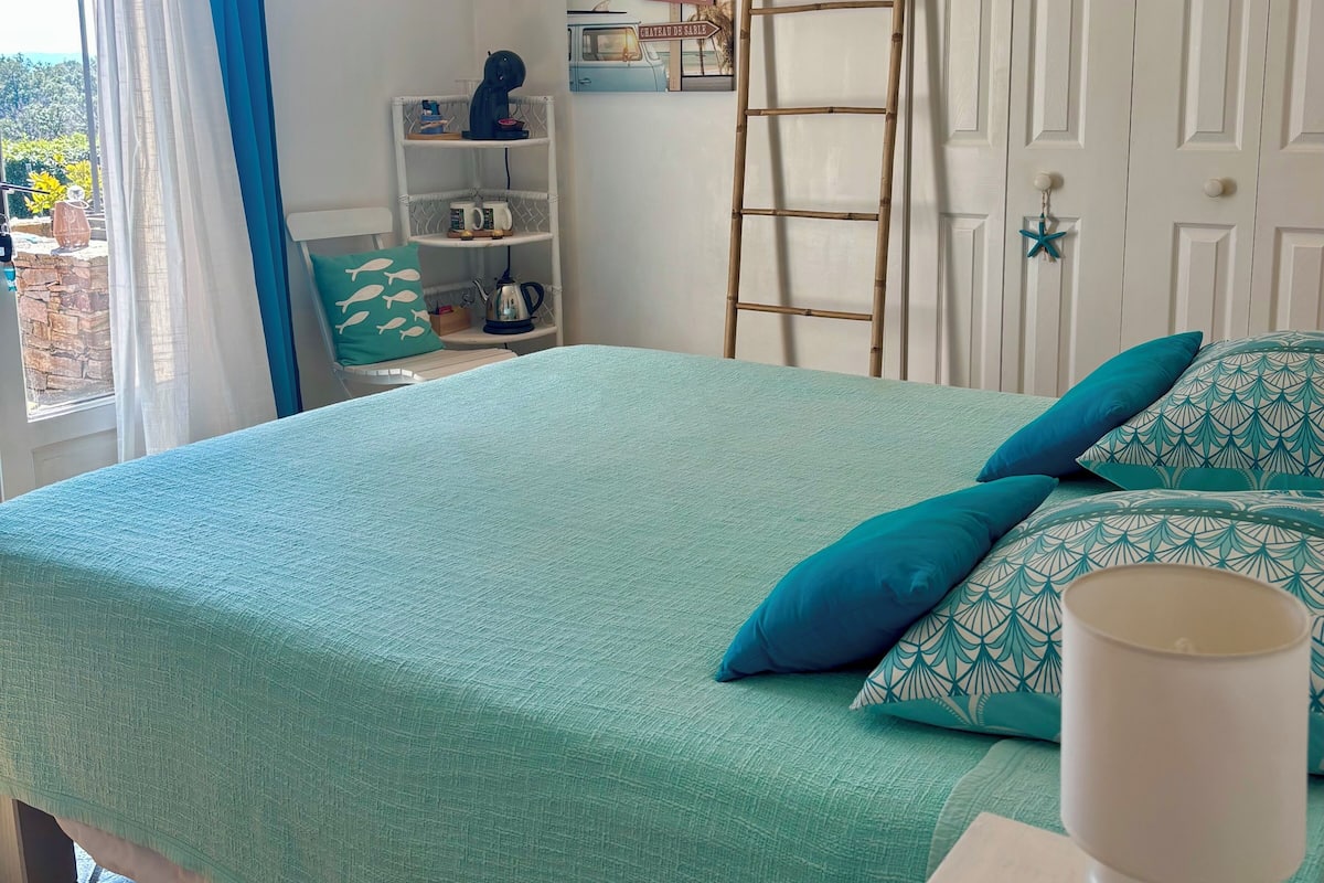 Un dormitorio con una cama, una escalera, una estantería con objetos y una puerta.