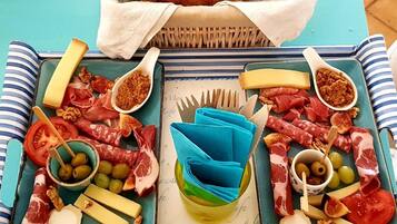 A charcuterie board with various meats, cheeses, and olives on a blue tablecloth.