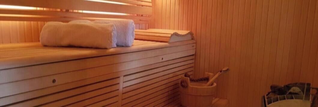 Sauna, jossa on puiset lauteet, pyyhe ja ämpäri.