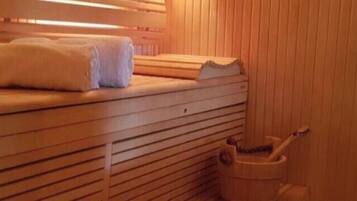 Eine Sauna mit Holzbänken, einem Handtuch und einem Eimer.