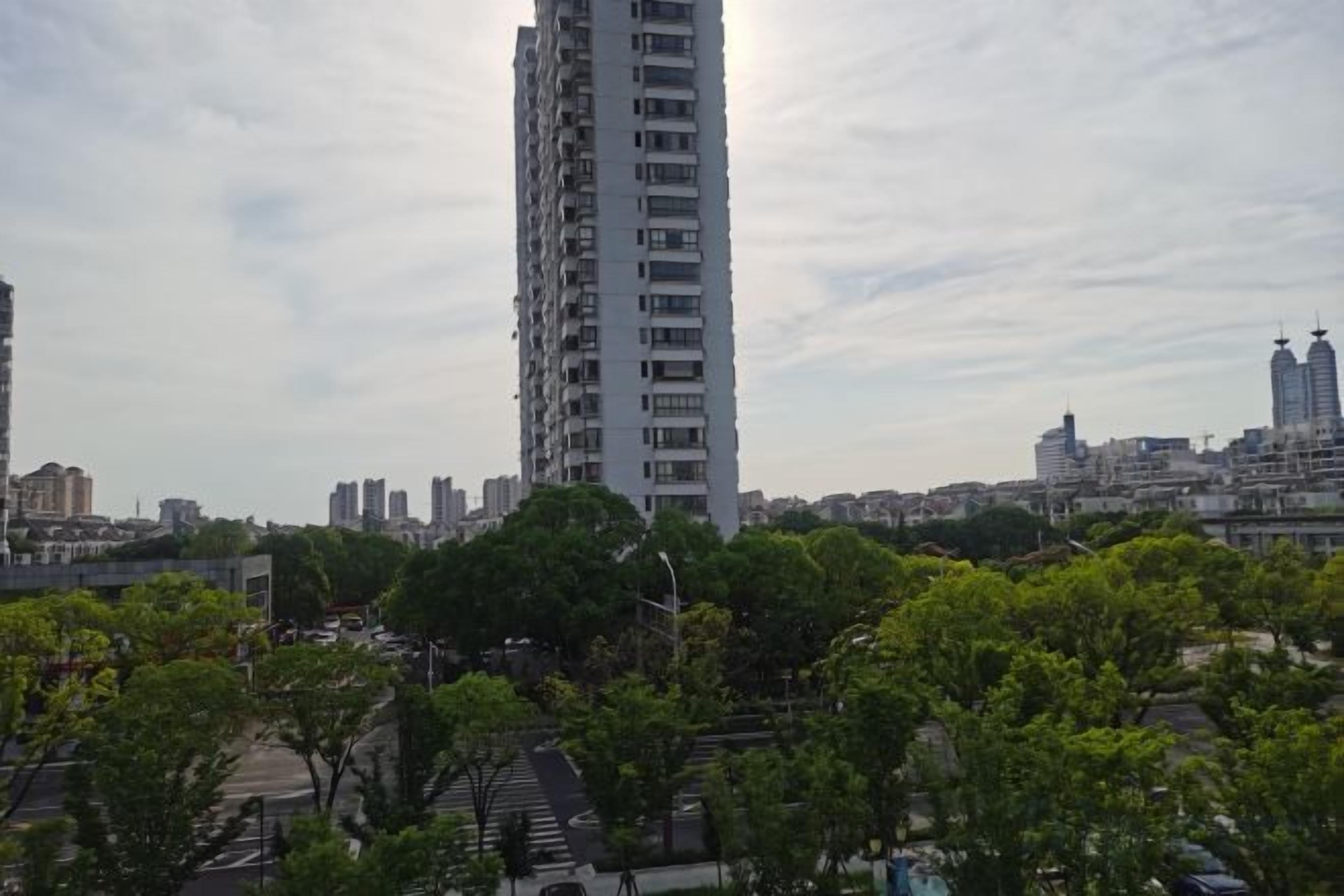 A high-rise building with a clear view of the surrounding urban landscape, including other buildings and a tree-lined street.