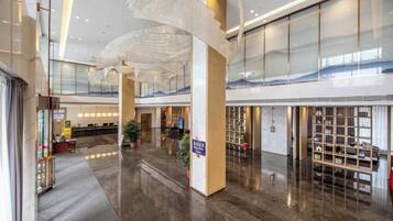 A spacious lobby with a reception desk, seating area, and a large glass wall.
