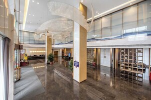 A spacious lobby with a reception desk, seating area, and a large glass wall.