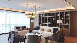A modern living room with a sofa set, armchairs, a coffee table, and a bookshelf. - Jintai Metropark Hotel (Taizhou)