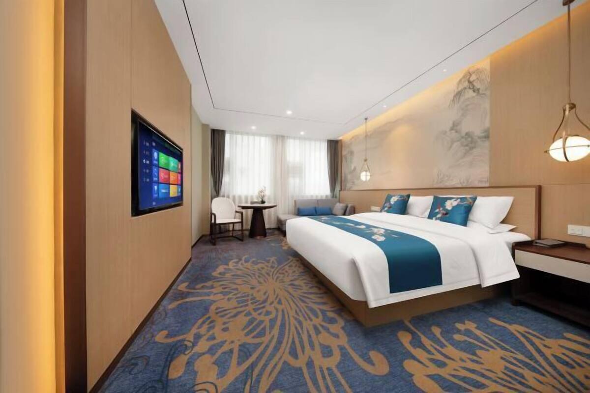 Una camera d'albergo con un letto grande, una scrivania, una sedia, una televisione e un quadro appeso al muro.
