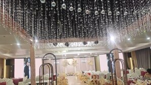 A banquet hall with tables set for a formal event, decorated with floral arrangements and hanging ornaments. - Jintai Metropark Hotel (Taizhou)