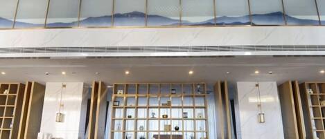 Un vestíbulo de hotel con techo alto, una gran exhibición de objetos decorativos y vistas del cielo a través del techo.