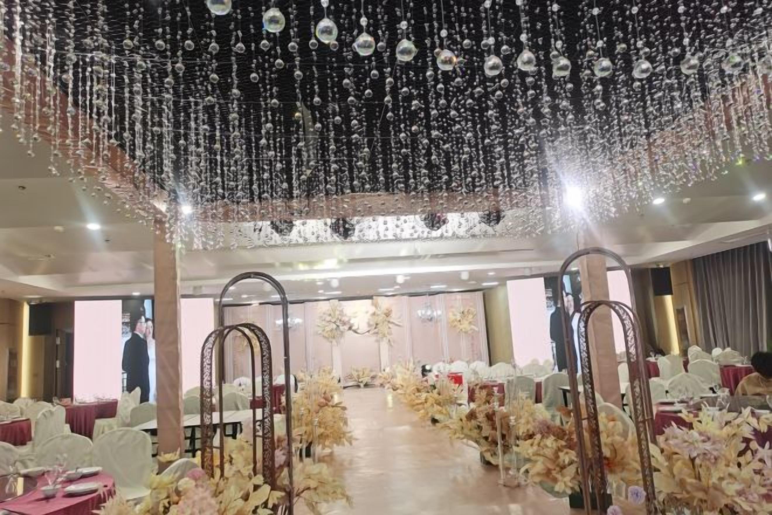 An indoor venue with rows of tables and chairs, a central aisle, and hanging decorations.