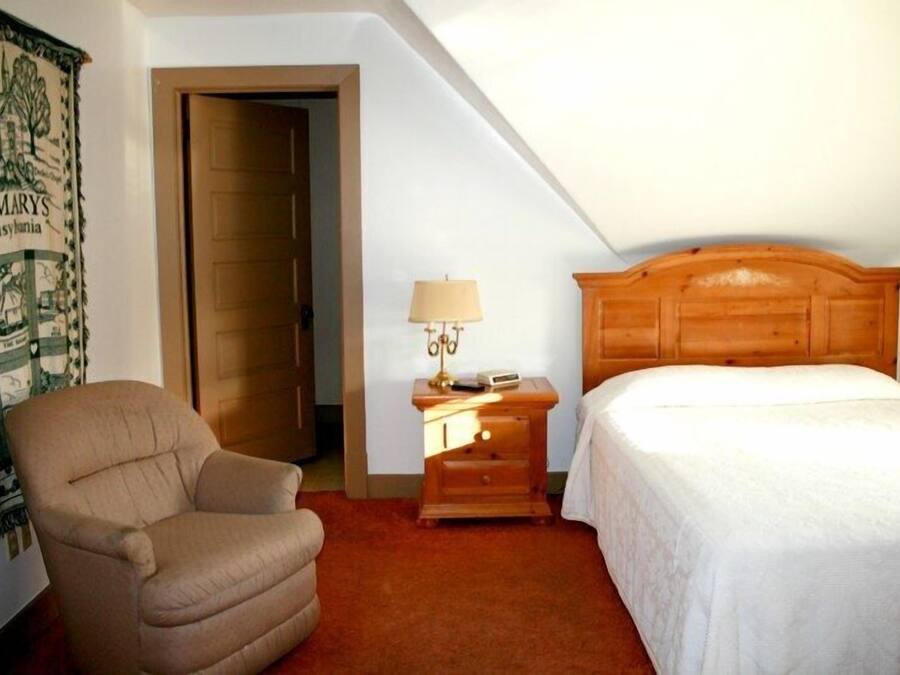 Une chambre à coucher avec un lit, une table de chevet, une lampe, une chaise et une porte.