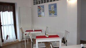 A dining area with white tables and chairs, red tablecloths, and two framed posters on the wall. - Magico Riposo (Telese)