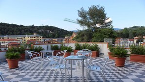 A rooftop terrace with checkered flooring, metal chairs, tables, and potted plants. - Magico Riposo (Telese)