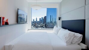 Una habitación de hotel moderna con una cama grande, un televisor en la pared y vistas a la ciudad.