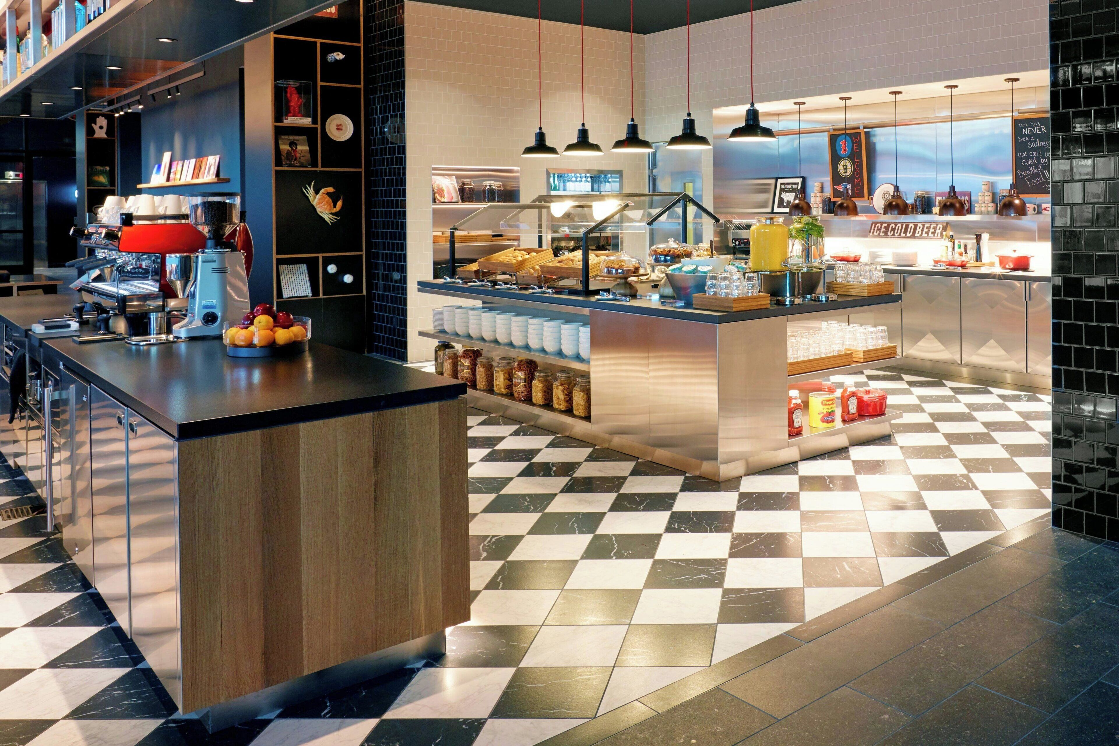 Una cafeteria moderna amb un terra de pissos de graella, una màquina de cafè i diversos plats exposats.