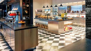 Una cafeteria moderna amb un terra de pissos de graella, una màquina de cafè i diversos plats exposats.