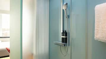A modern shower enclosure with a glass door, a handheld showerhead, and a wall-mounted control panel.