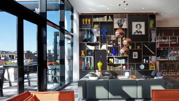 Una sala de estar moderna con un sofá, una mesa de centro y una estantería llena de libros y objetos decorativos.