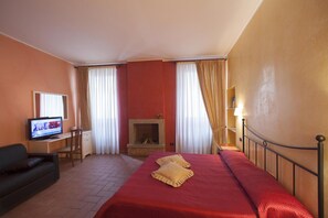 A hotel room with a bed, a television, a desk, and a fireplace. - B&B Sant'Antonio De Foris (Bergamo)