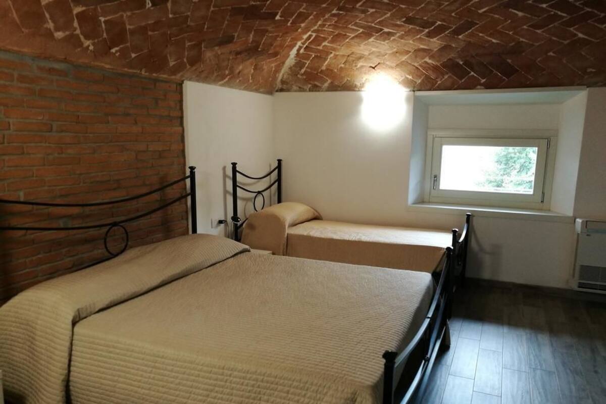 Ein Zimmer mit Ziegeldecke, einem Bett mit Kopfteil, einem Fenster und einer Heizung.
