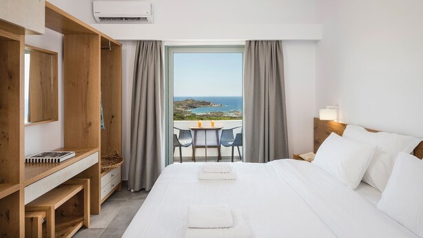 Une chambre d’hôtel avec un lit, un bureau, une chaise et une vue sur la mer.