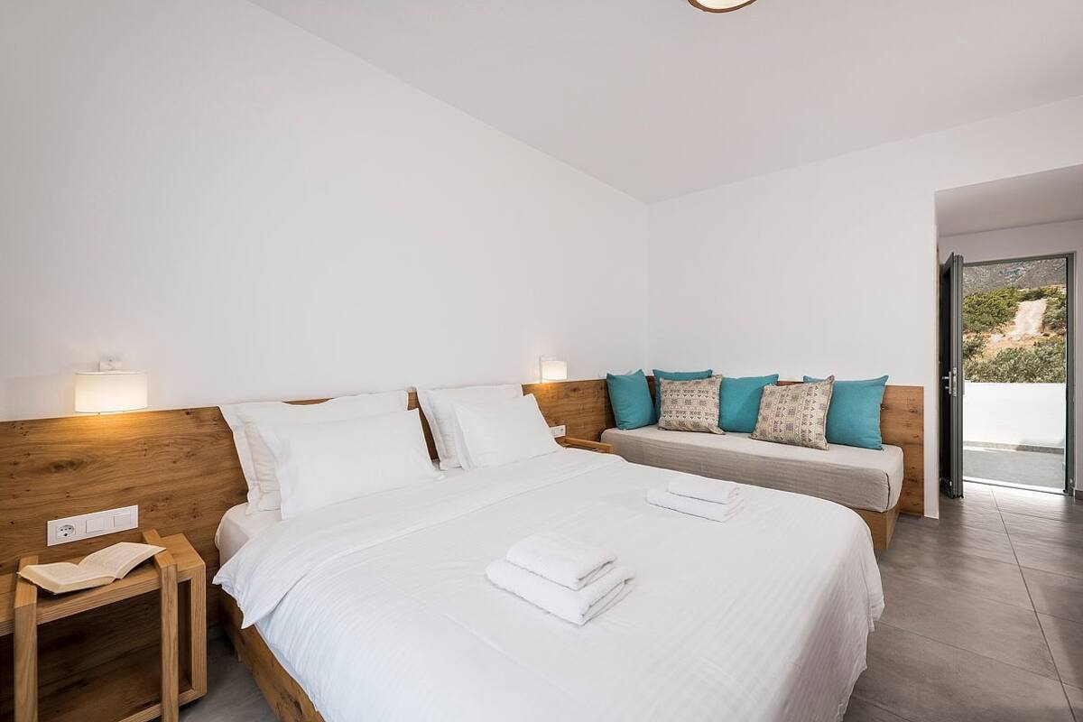 Una habitación de hotel moderna con una cama grande, dos mesitas de noche y vistas al exterior.