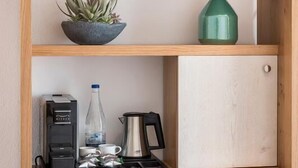 Une petite cuisine équipée d’une machine à café, d’une bouilloire, d’une bouteille d’eau et d’un petit placard.