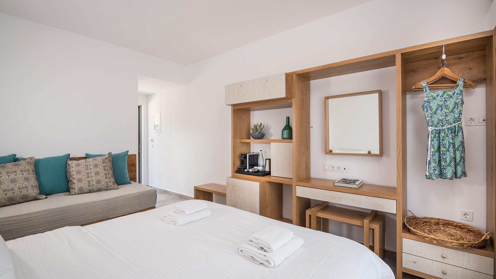 Un dormitorio moderno con una cama grande, un armario de madera, un espejo y un vestido colgado.