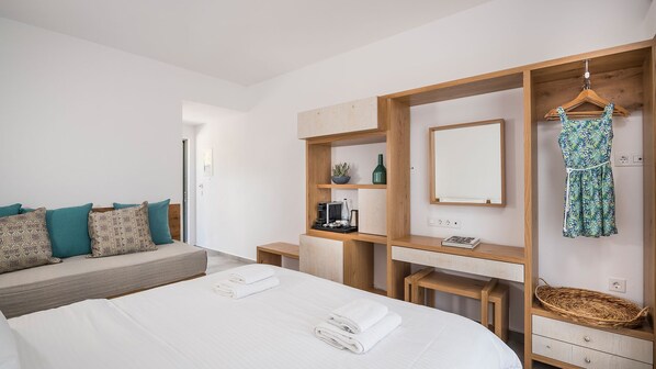A modern bedroom with a large bed, a wooden wardrobe, a mirror, and a hanging dress. - Glykeria Hotel (Kissamos)