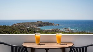 Un balcon avec deux verres de jus d’orange et une vue sur la mer.