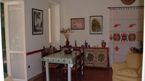 A dining area with a table and chairs, a sofa, and decorative wall art.