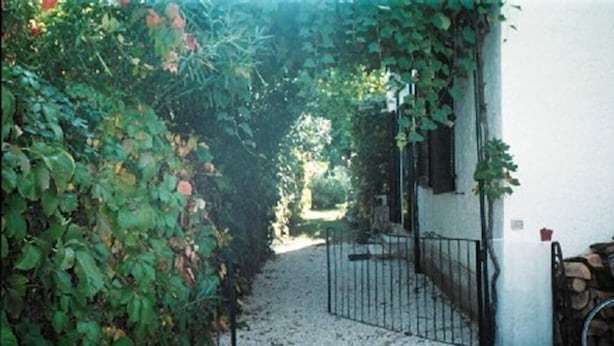 A gravel pathway leading to a gated entrance surrounded by dense foliage.