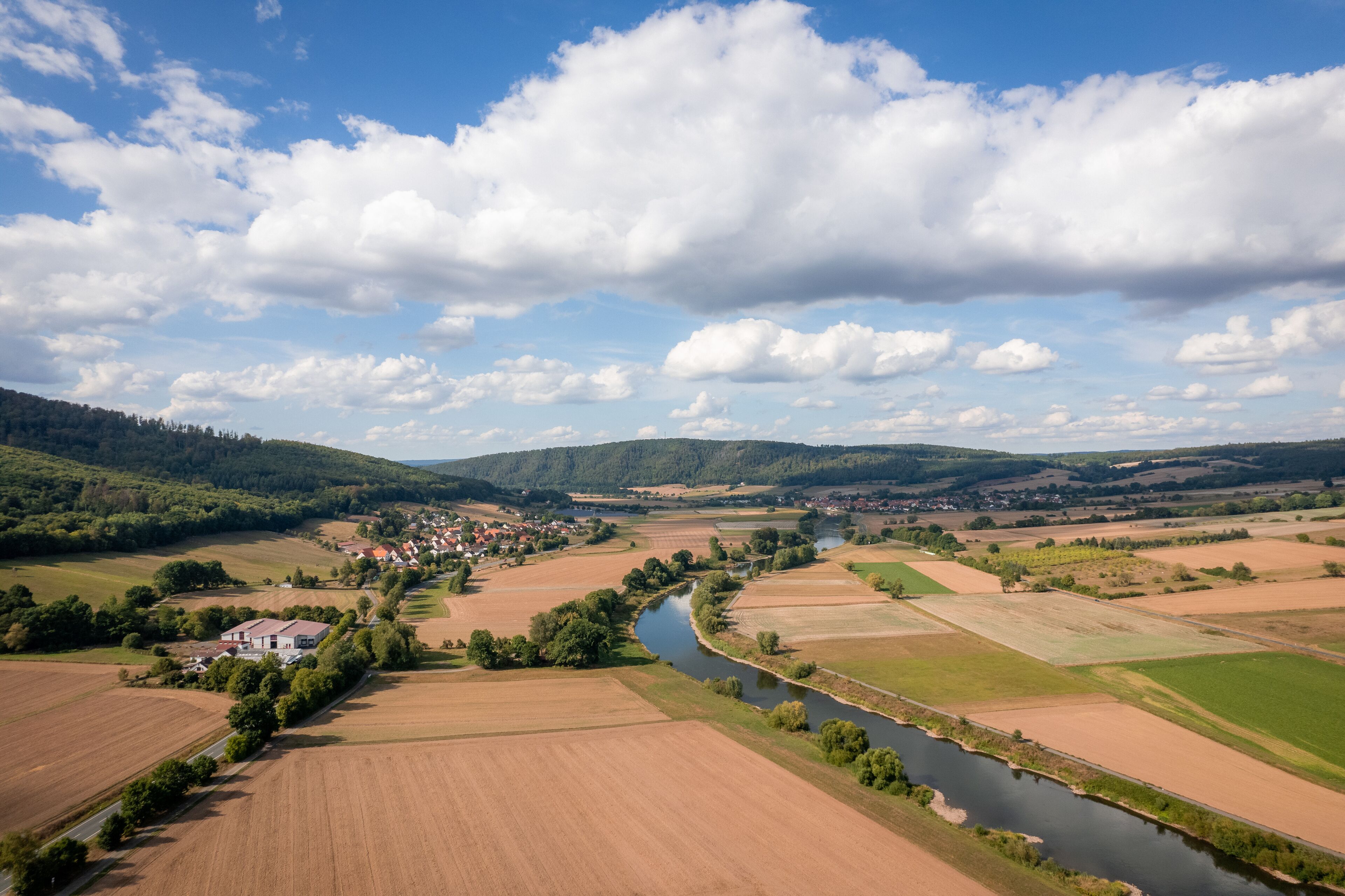 Ländliche Landschaft mit Fluss, Feldern und einem kleinen Dorf.