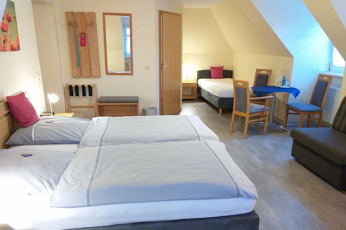 Une chambre avec deux lits, un bureau, une chaise et un canapé.
