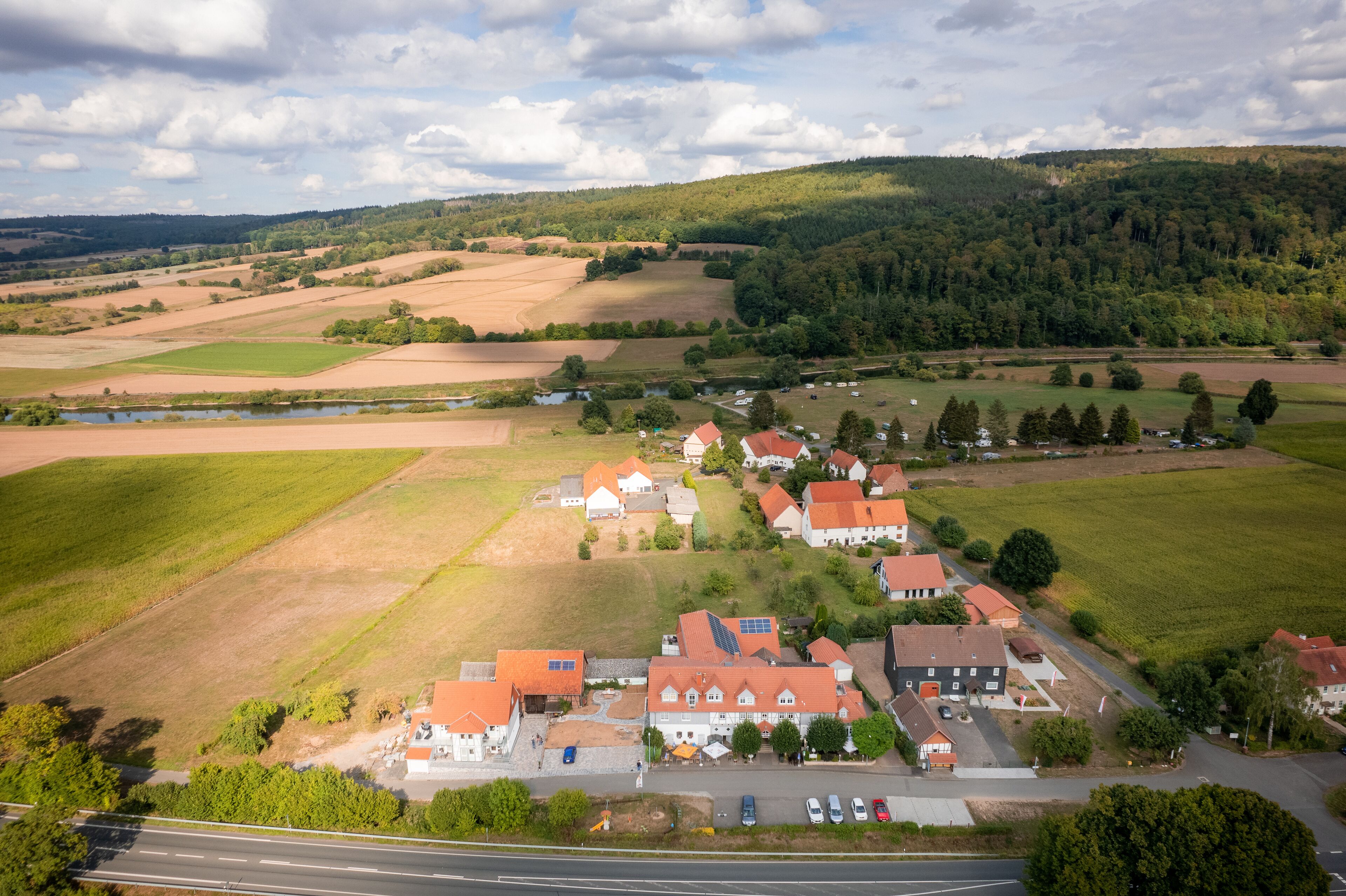 An aerial view of a rural village with houses, fields, and a river.