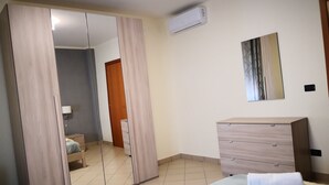 A bedroom with a large mirror, a wardrobe, a dresser, and a bed.