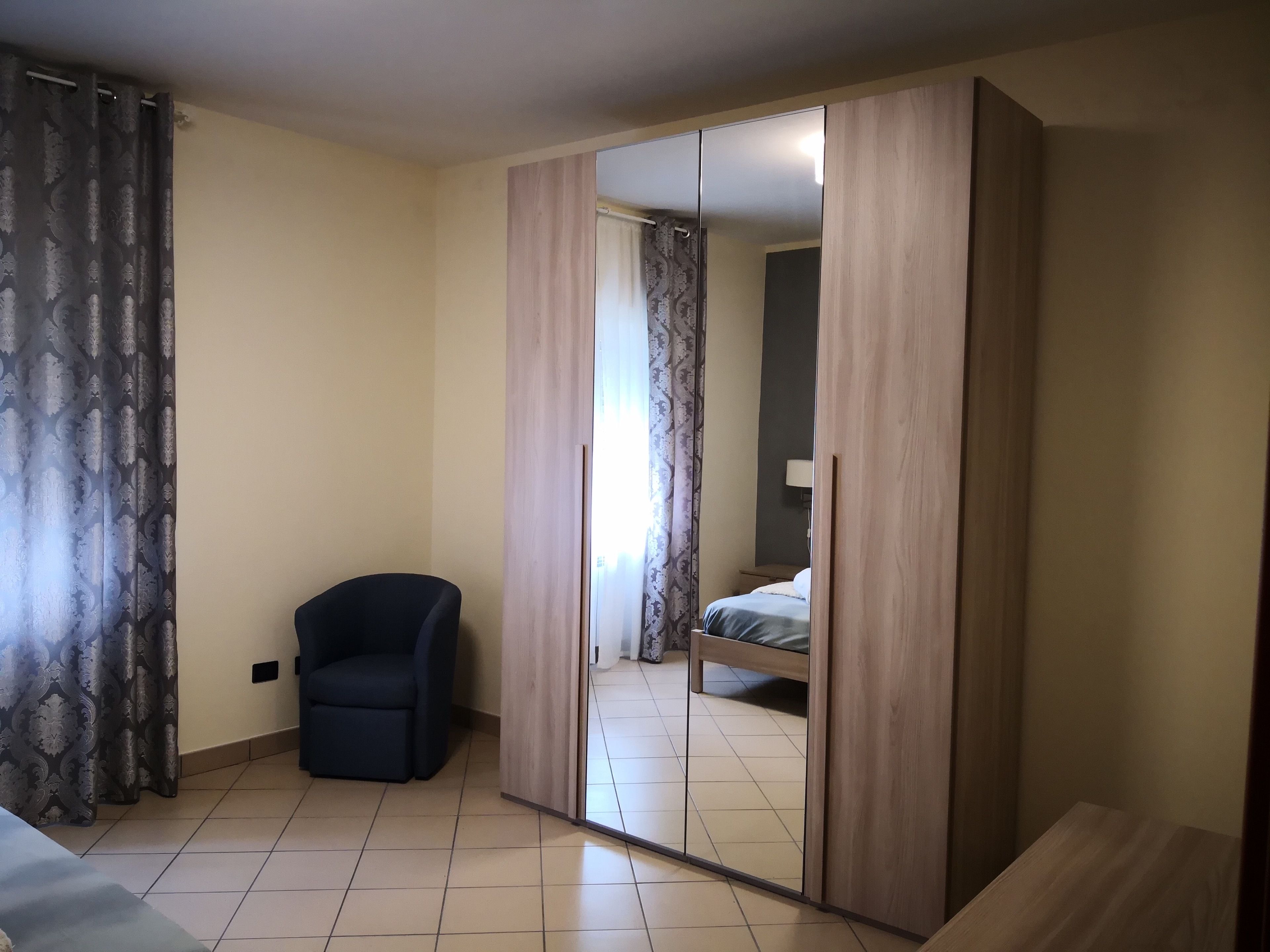 A bedroom with a bed, a chair, and a wardrobe.