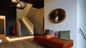 Una sala moderna con sofá, una escalera y un espejo grande en la pared.
