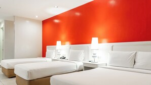 A hotel room with three beds, white bedding, and a red accent wall. - Ecotel by L'Fisher (Bacolod)