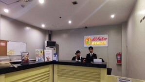 A hotel reception desk with two staff members, a sign for 'L'Hotel', and a 'Authorized Personnel Only' sign. - Ecotel by L'Fisher (Bacolod)