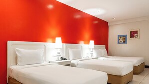 A hotel room with two beds, white bedding, and a red accent wall. - Ecotel by L'Fisher (Bacolod)