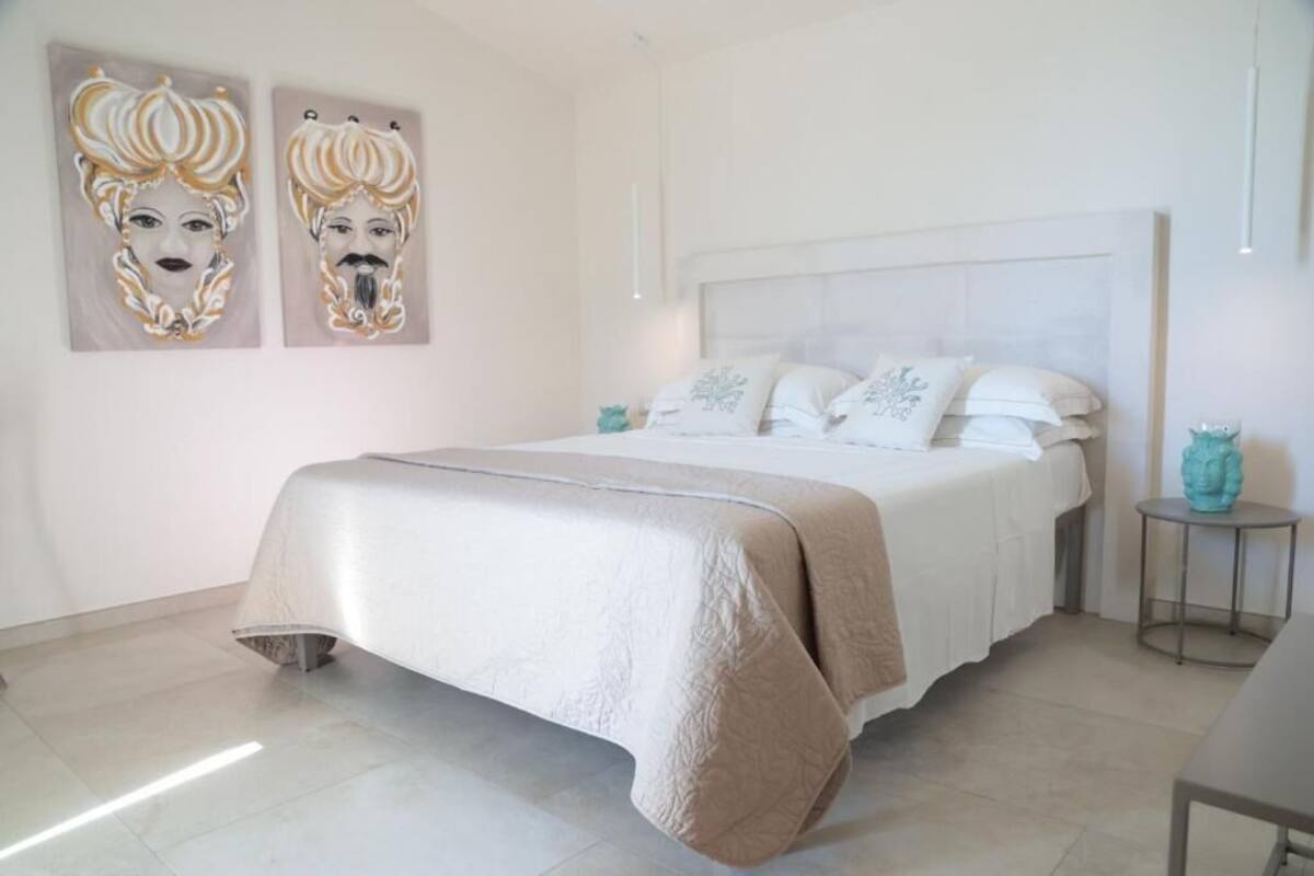 A bedroom with a large bed, a bedside table, and two wall-mounted artworks.