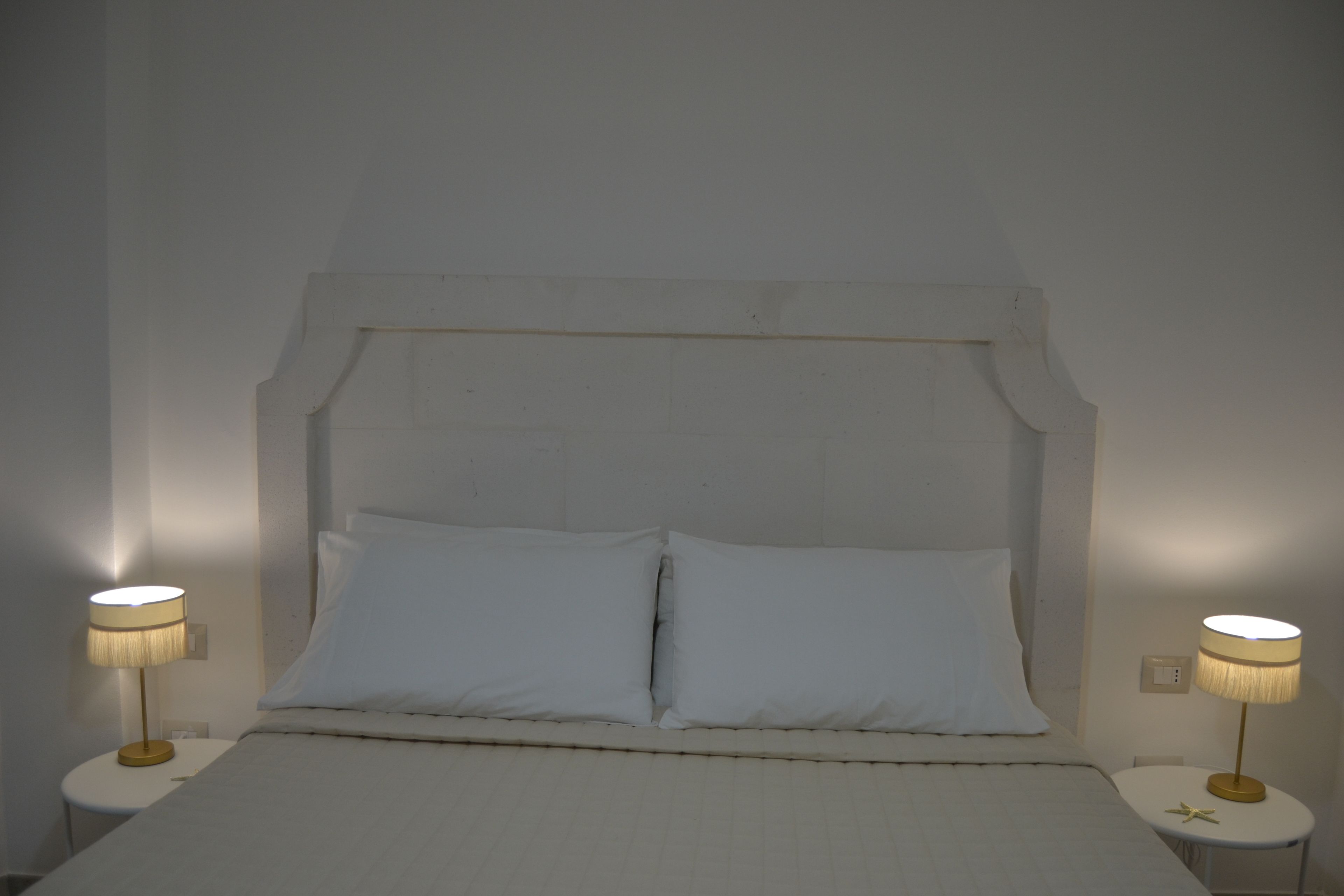 A bed with white bedding, two bedside tables with lamps, and a simple headboard.
