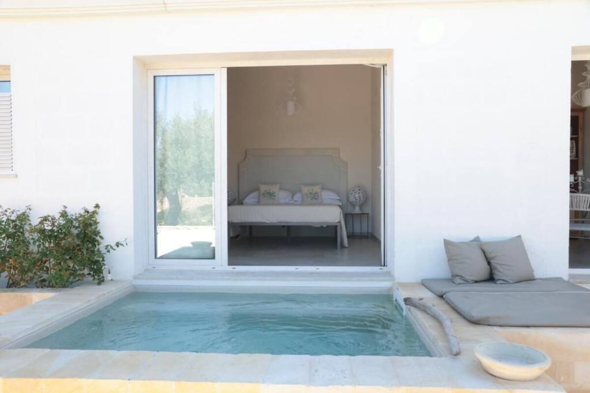 A bedroom with a bed, a small bedside table, and a window.