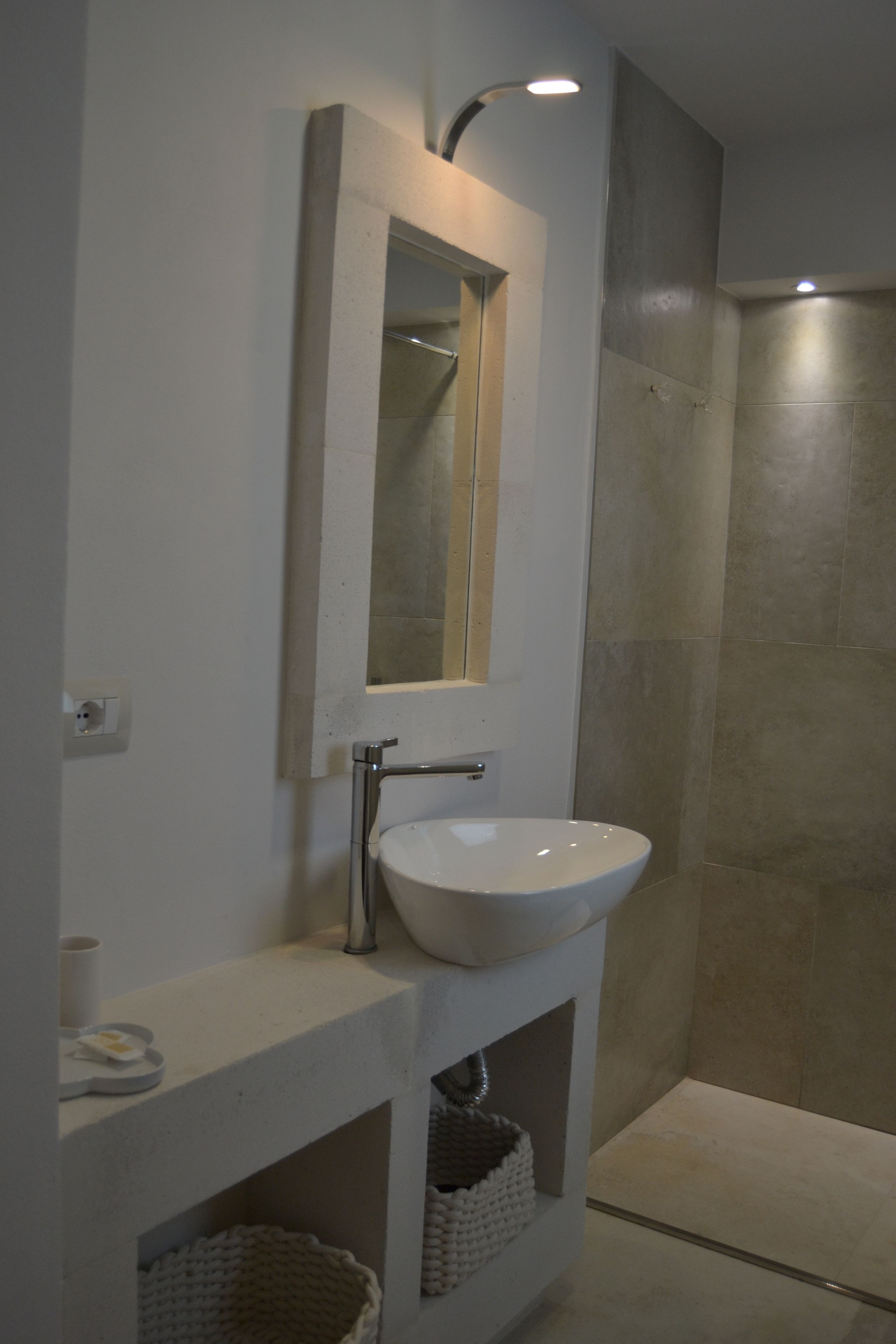 A bathroom with a white sink, a mirror, and a shower area.