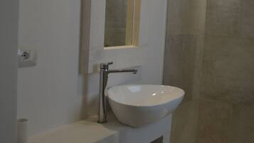 A bathroom with a white sink, a mirror, and a shower area.