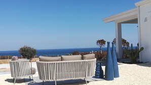 Un patio con dos sillones acolchados orientados hacia una vista del mar.