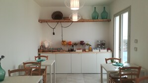 Una cocina con armarios blancos, encimera de madera y lámpara colgante. Hay dos jarrones verdes en un estante sobre la encimera.